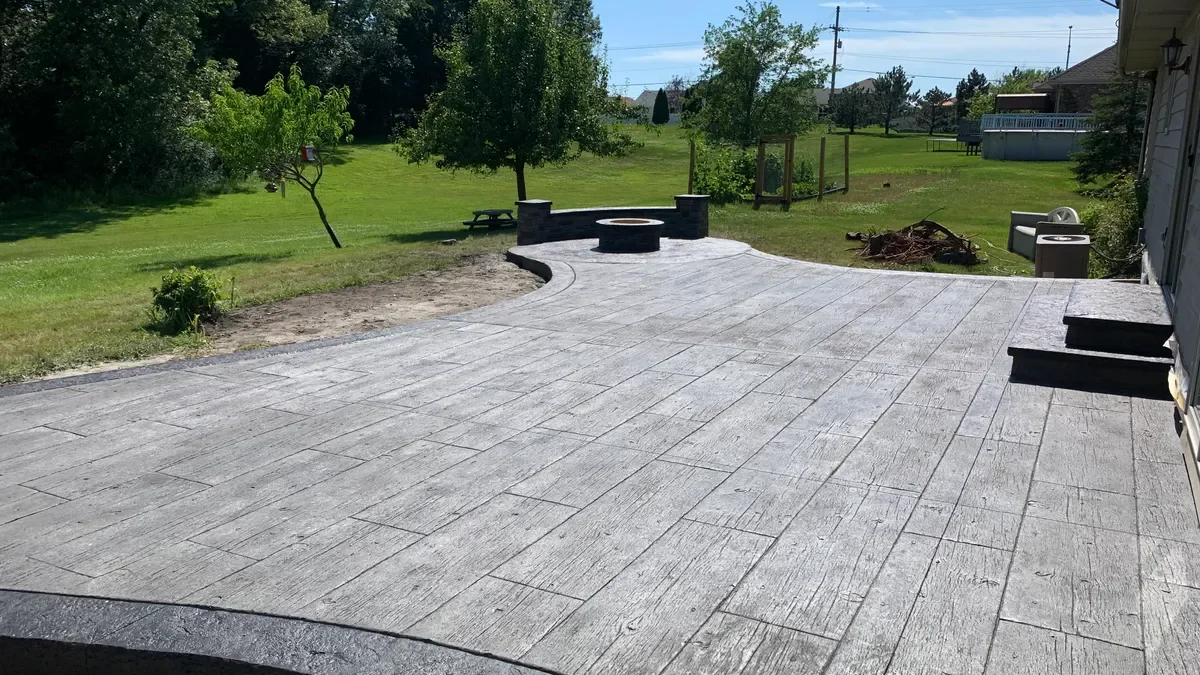 Gray stamped concrete patio with a circular fire pit