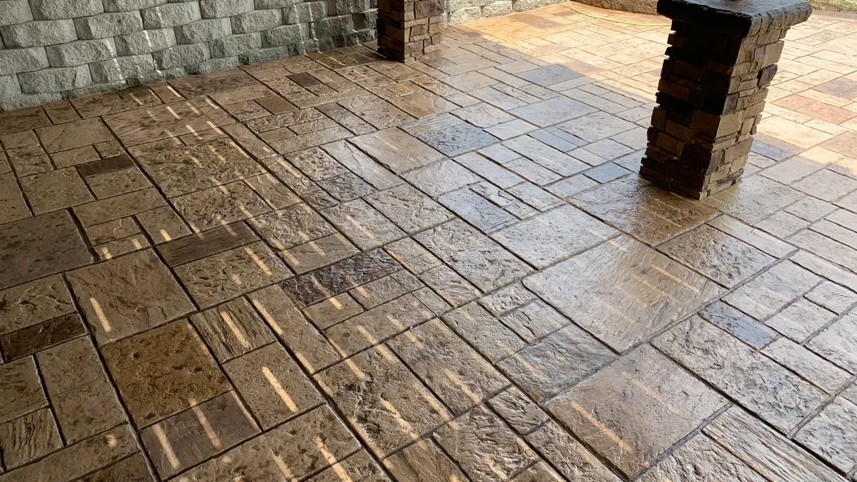 Stone-pattern stamped concrete patio beside masonry pillars