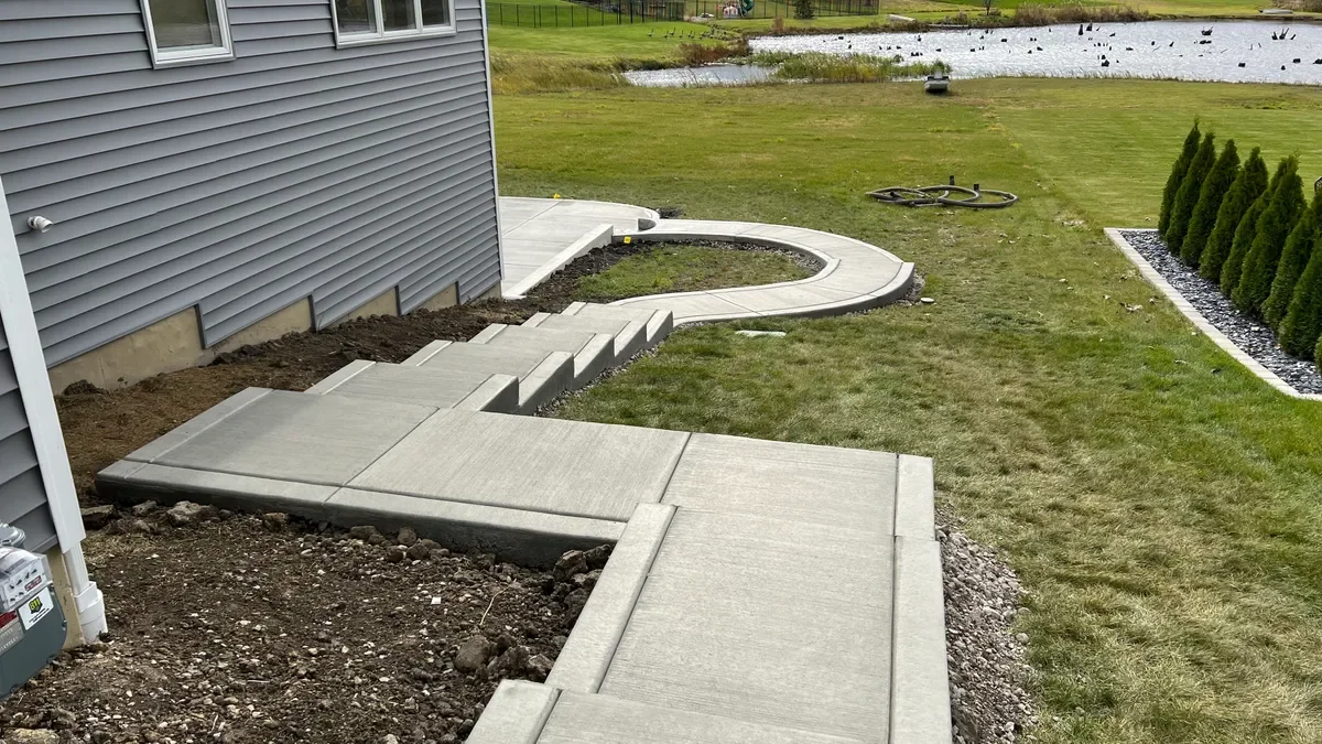 Concrete steps and curved walkway beside a home